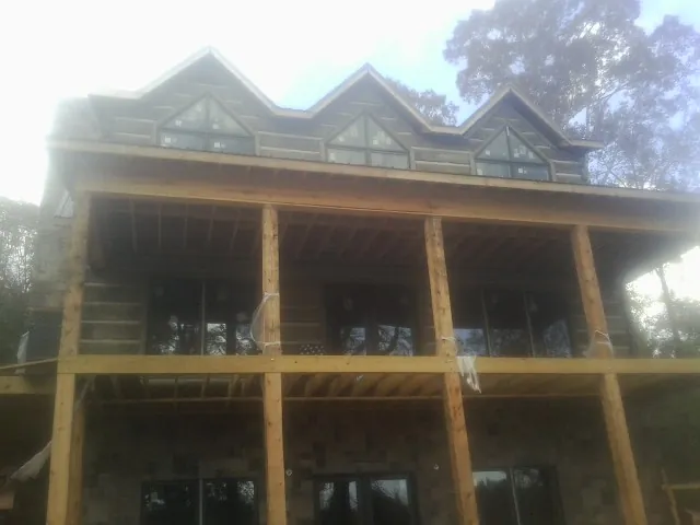 Dormers and porch framing on a large log home under construction — Roof Coating work by our crew in Buffalo Lake