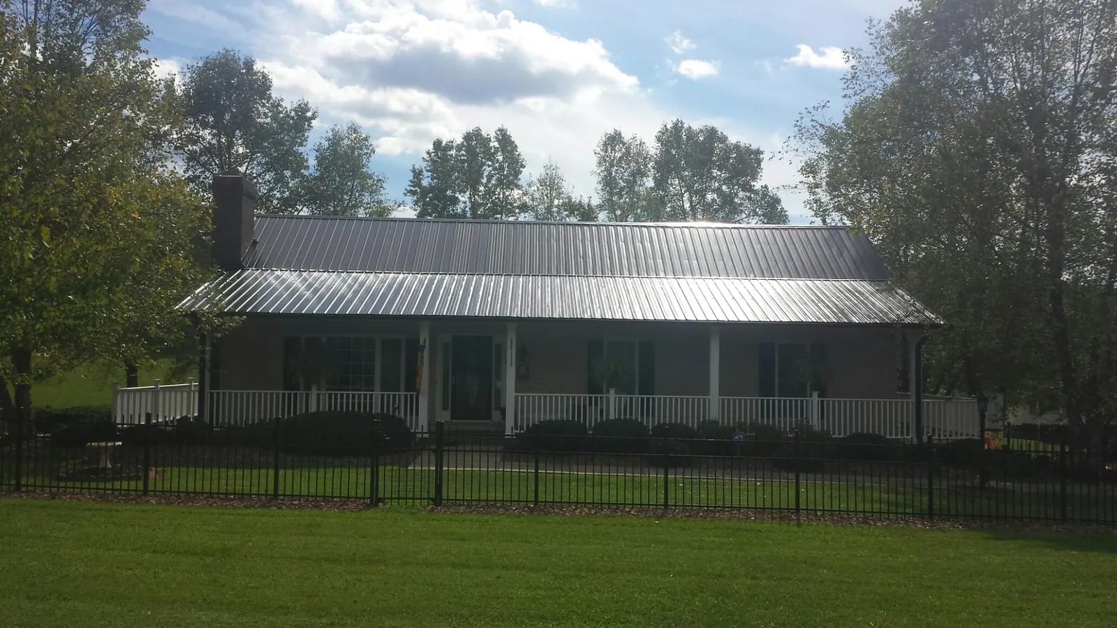 Gray metal roof on a brick ranch with a full width front porch — Gutter Guard Installation work by our crew in Buffalo Lake