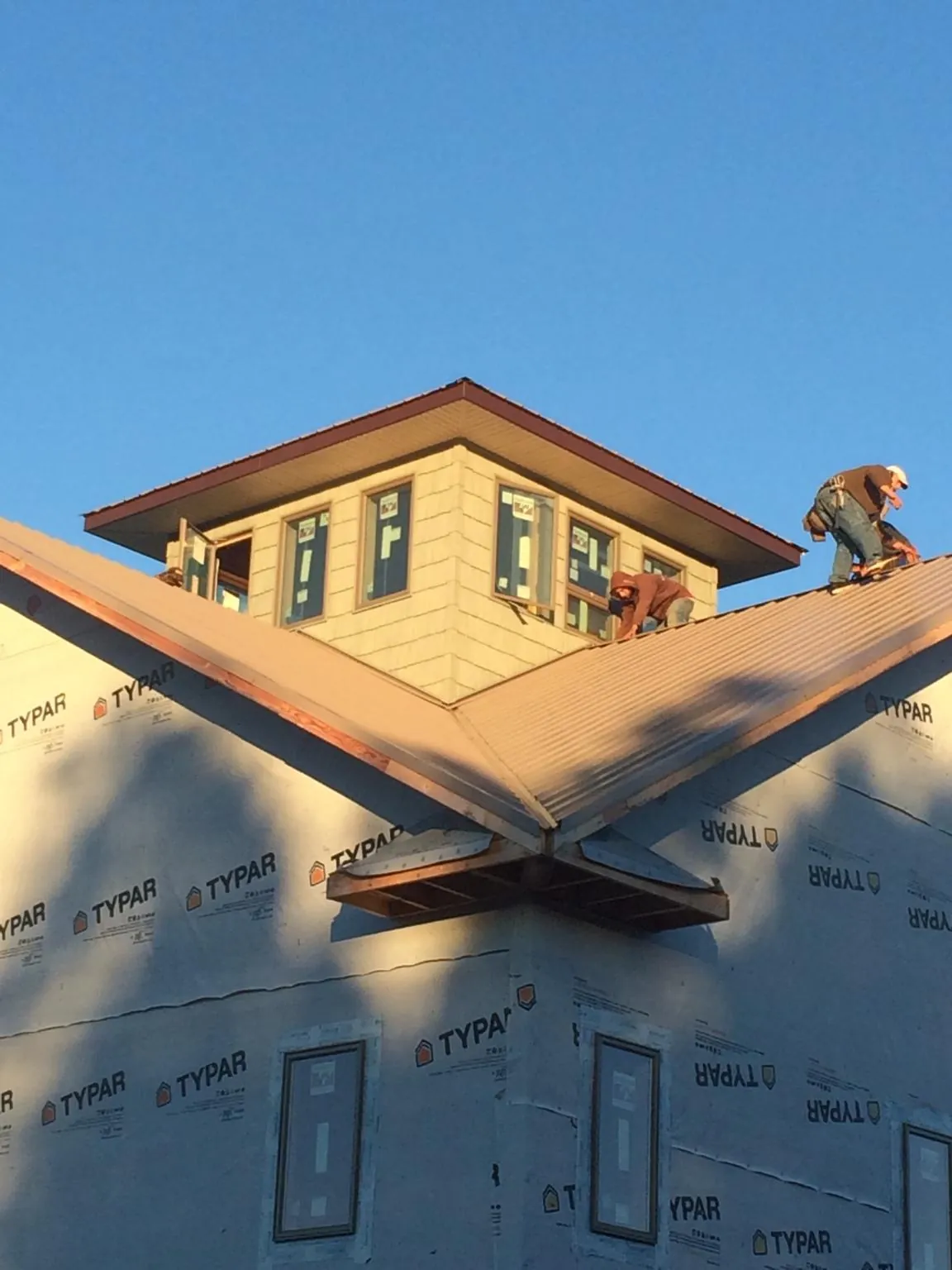 Roofers working around a rooftop cupola on a new metal roof at sunset — Roof Waterproofing in Buffalo Lake by Roofing Brothers